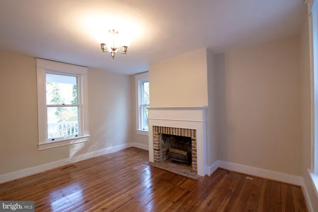 an empty room with wooden floor a fireplace and windows