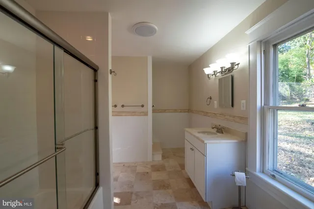 a bathroom with a double vanity sink a toilet a shower and a mirror