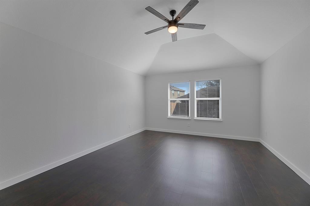 605 Clearbrook Street Azle, TX 76020 - Photo 14 of 33 Vaulted ceiling room featuring dark wood-finish flooring, two windows with blinds, and a ceiling fan with integrated lighting