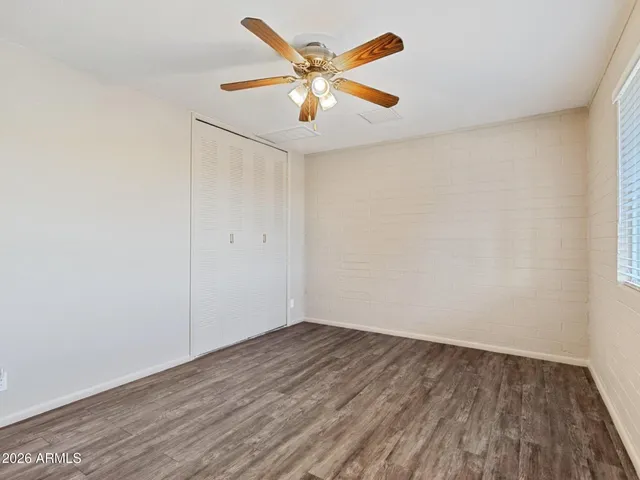 an empty room with wooden floor and ceiling fan