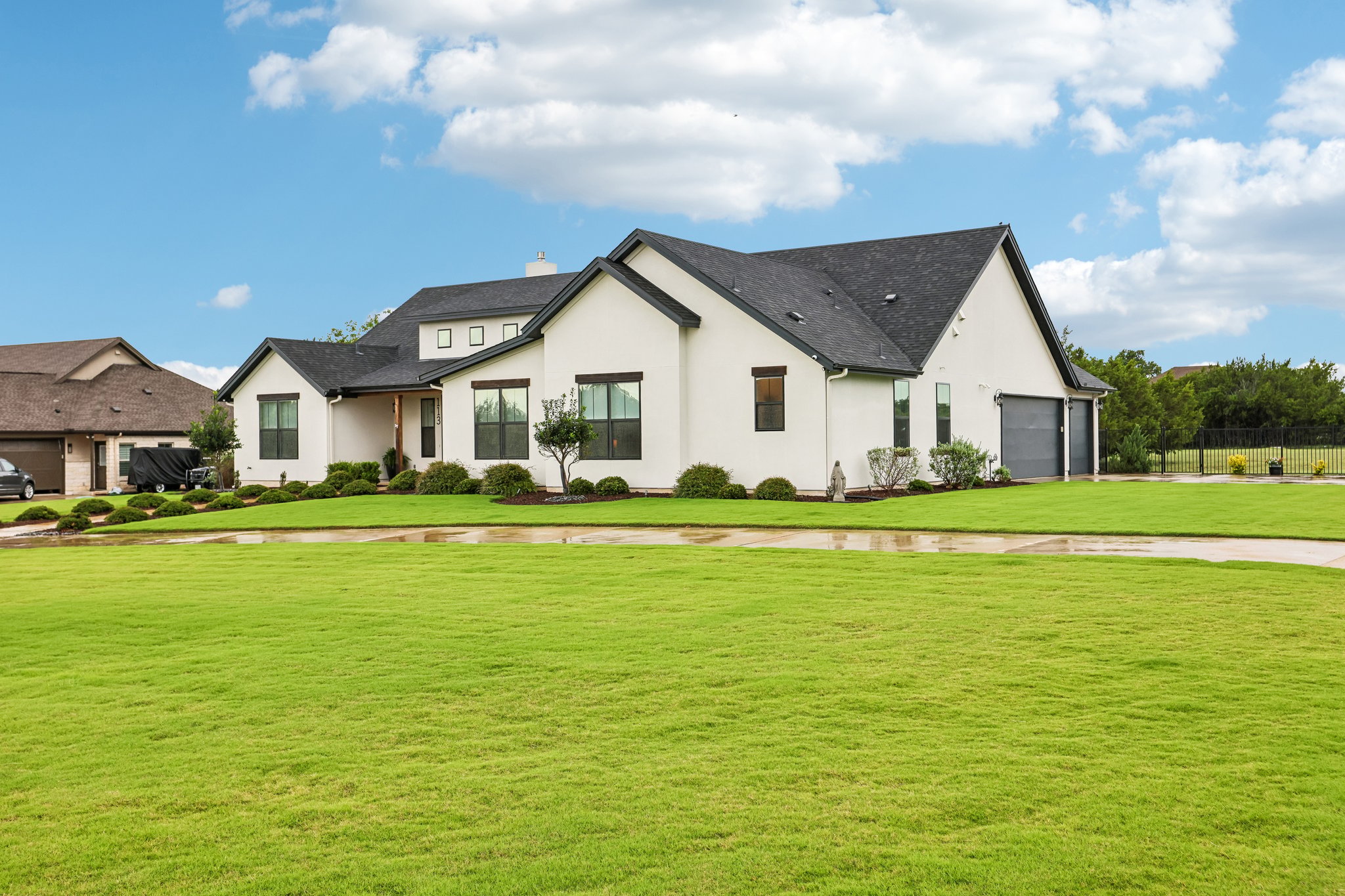 113 Crystal Lane Georgetown, TX 78633 - Photo 11 of 32 An immaculate green lawn extends before a contemporary white home with a dark roof and integrated garage.