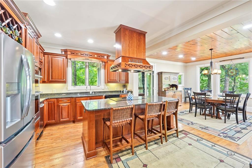 44 Sassafras Ridge Big Canoe, GA 30143 - Photo 25 of 107 a dining hall with stainless steel appliances granite countertop a stove a refrigerator a dining table and chairs with wooden floor