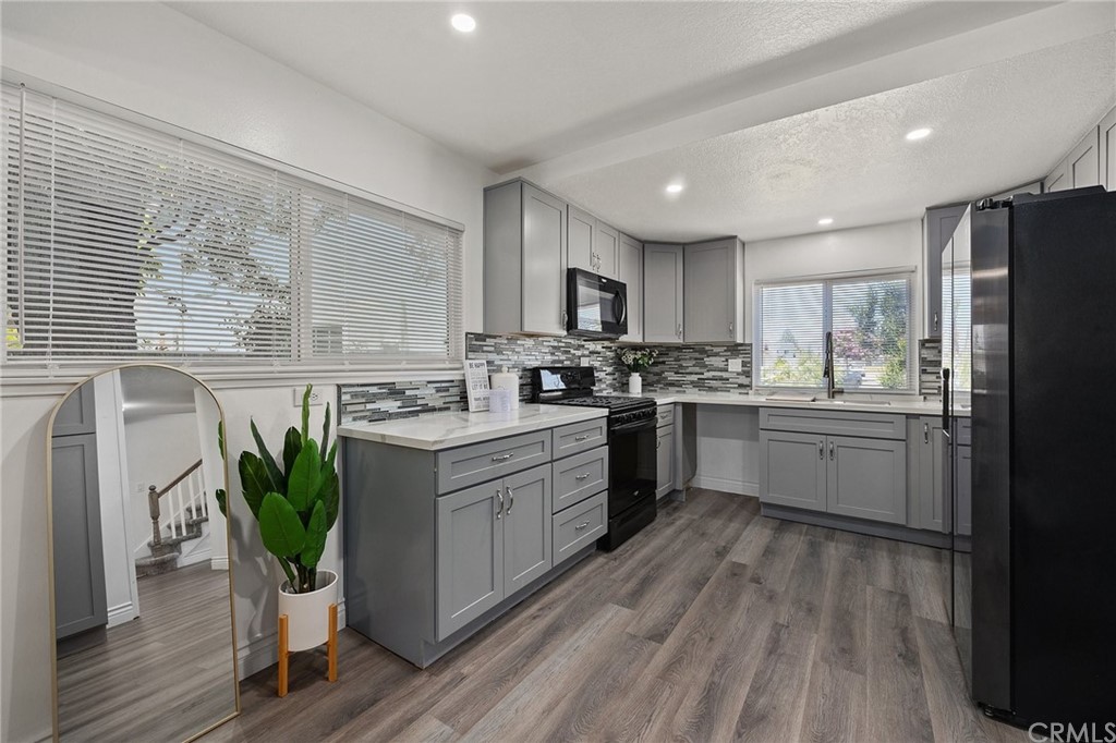 10221 Beaver Circle Cypress, CA 90630 - Photo 3 of 26 a kitchen with stainless steel appliances a sink a stove a refrigerator cabinets and a wooden floor