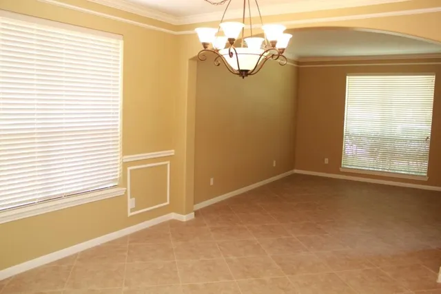 en empty room with windows and chandelier