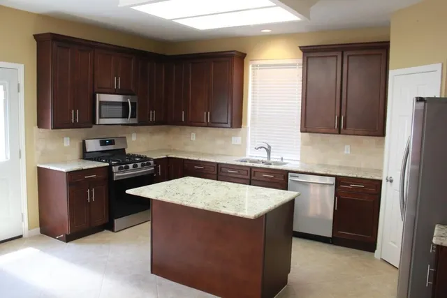 a kitchen with stainless steel appliances granite countertop wooden cabinets a stove top oven a sink and dishwasher