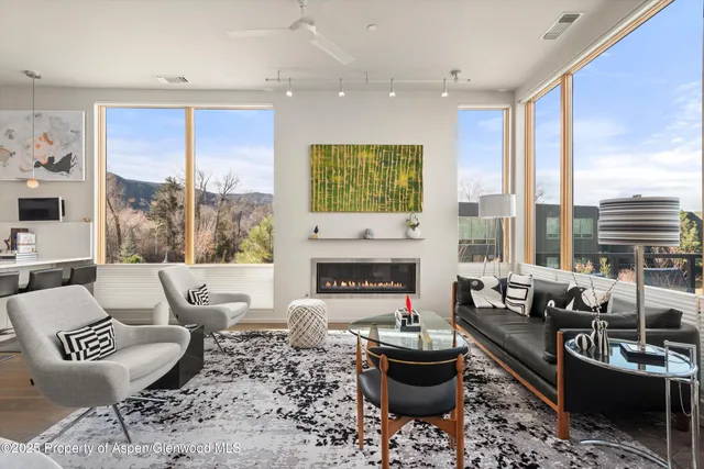 a living room with furniture a fireplace and large windows