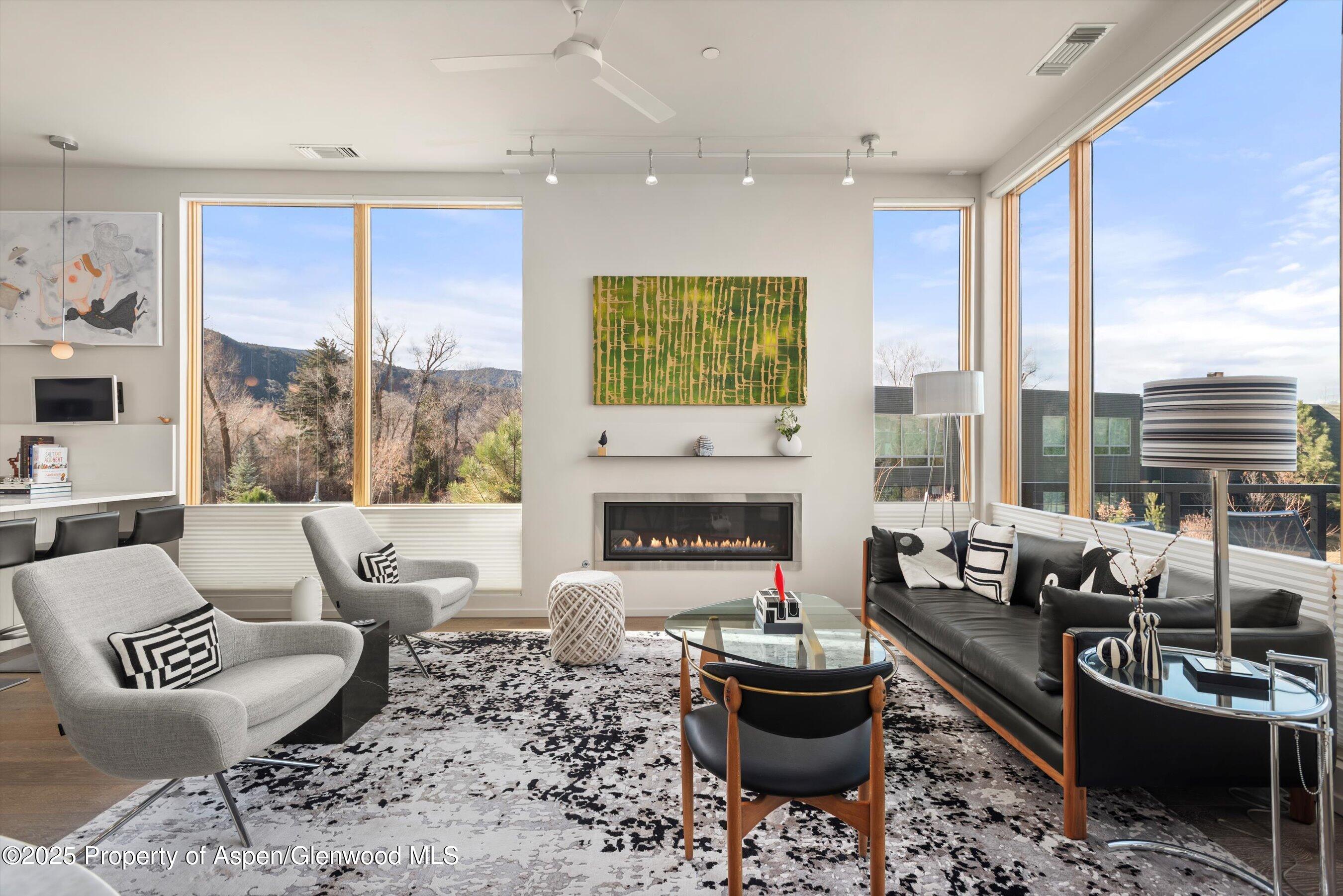 a living room with furniture a fireplace and large windows