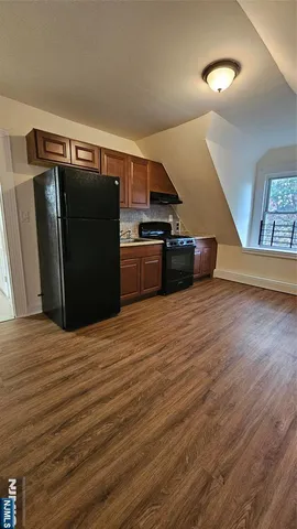 a kitchen with stainless steel appliances wooden floor and a refrigerator