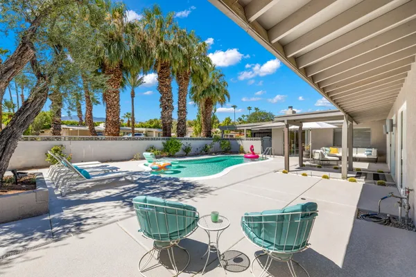 a view of a patio with table and chairs potted plants and palm trees