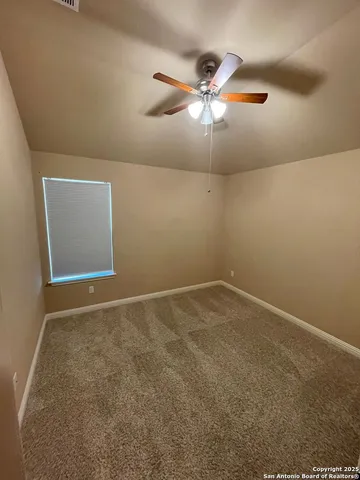 an empty room with a fan & a window