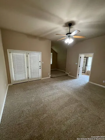 an empty room with chandelier fan and windows