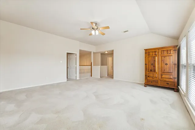 an empty room with chandelier fan and windows