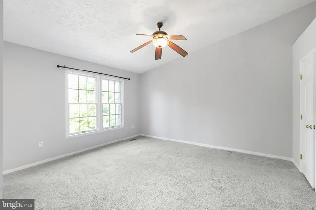 an empty room with chandelier fan and windows