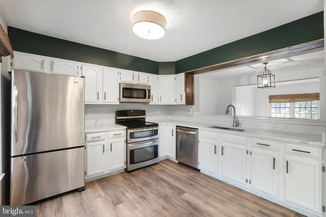 a kitchen with granite countertop a refrigerator stove a sink and dishwasher with wooden floor