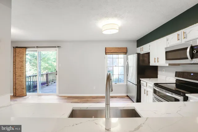 a living room with stainless steel appliances kitchen island granite countertop a refrigerator and a stove top oven