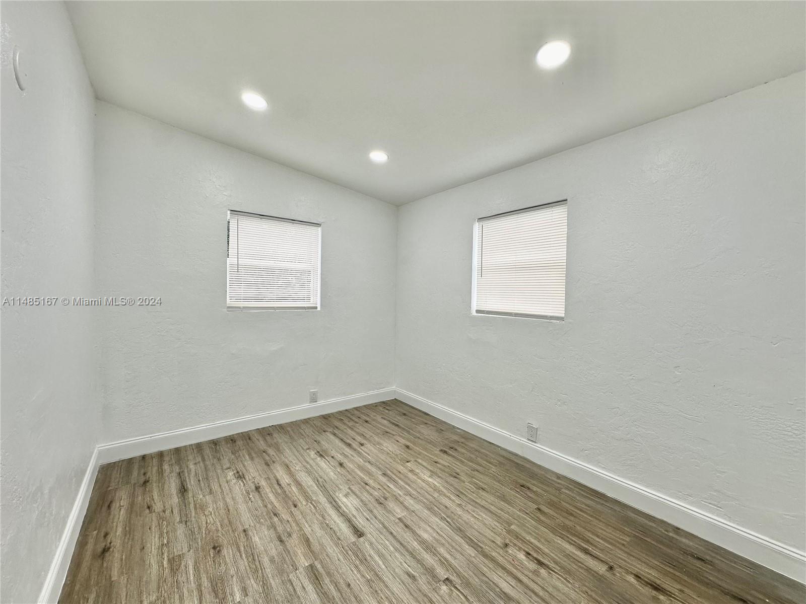 11470 Southwest 215th Street Miami, FL 33189 - Photo 13 of 18 an empty room with wooden floor and windows
