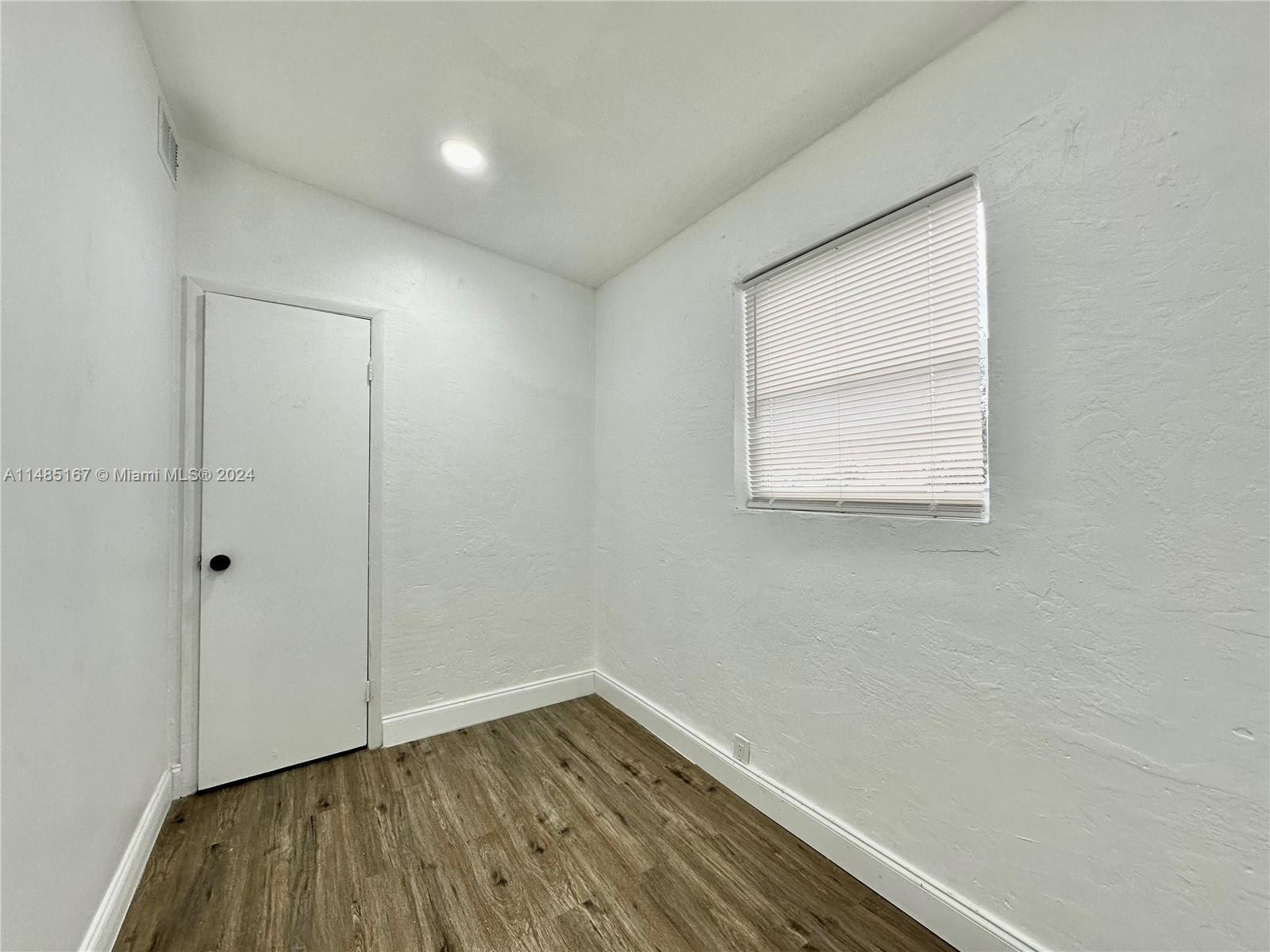 11470 Southwest 215th Street Miami, FL 33189 - Photo 15 of 18 an empty room with wooden floor and windows