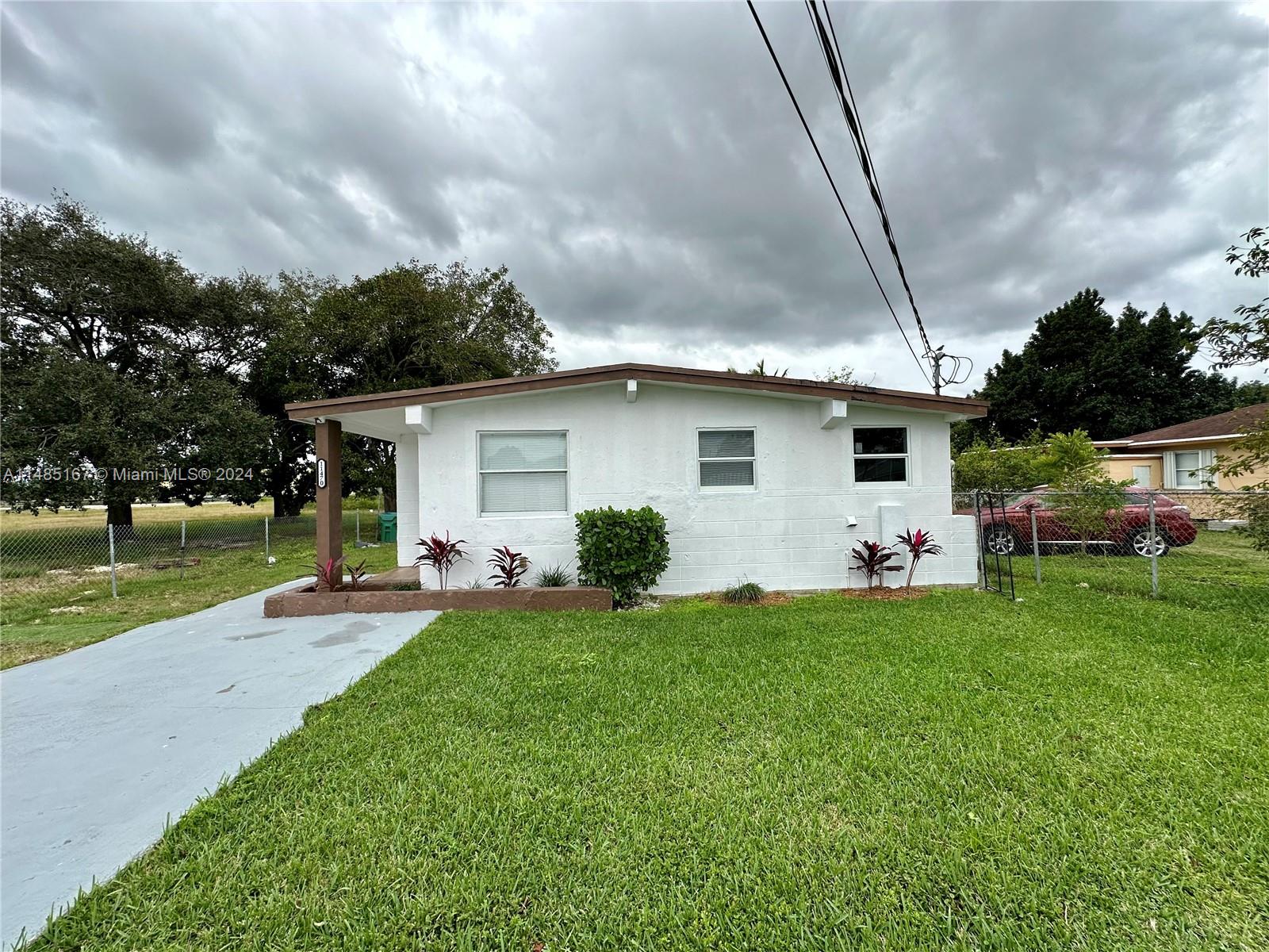 11470 Southwest 215th Street Miami, FL 33189 - Photo 2 of 18 a front view of a house with a yard and trees
