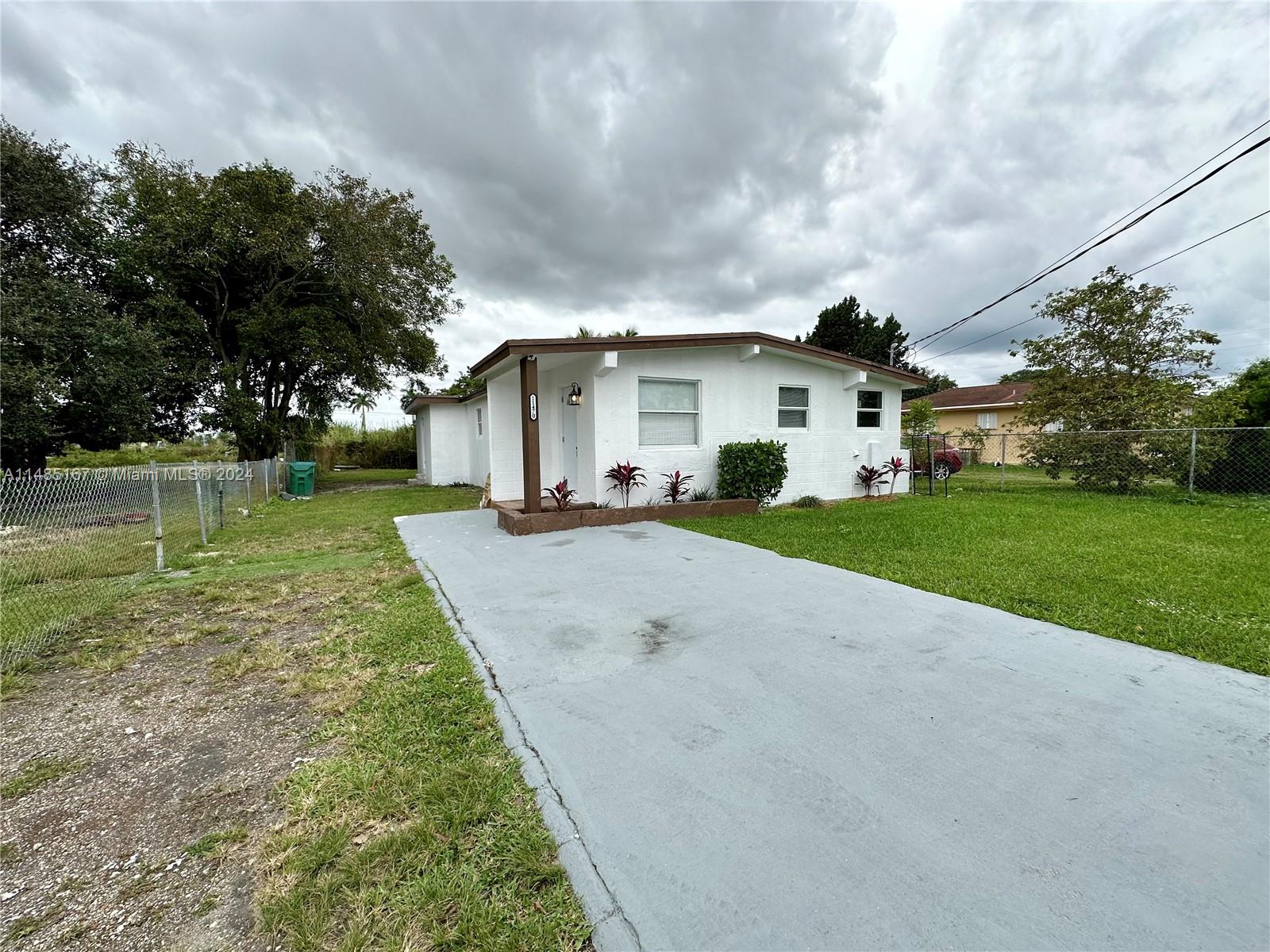 11470 Southwest 215th Street Miami, FL 33189 - Photo 3 of 18 a view of a white house next to a yard with big trees
