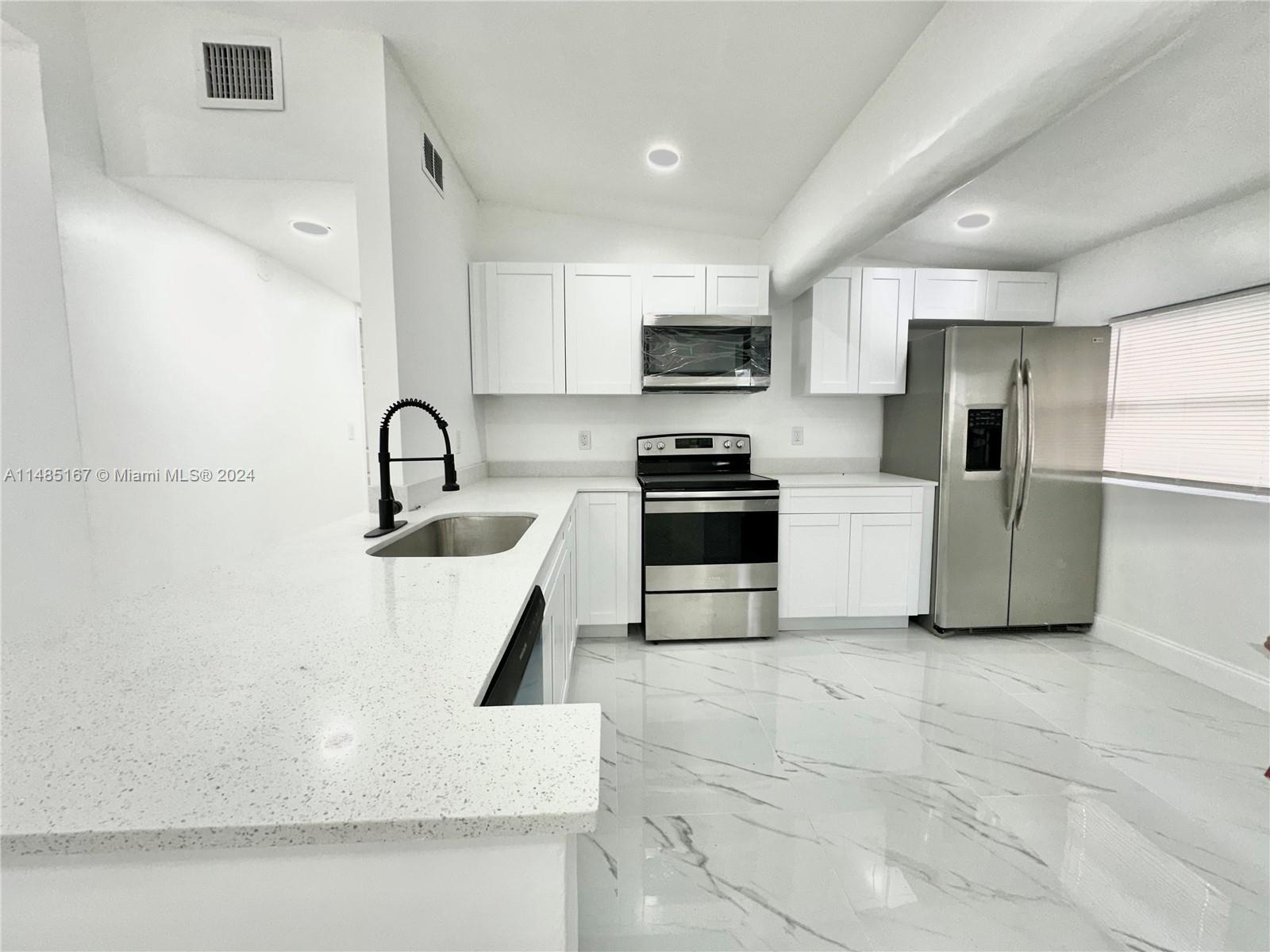 11470 Southwest 215th Street Miami, FL 33189 - Photo 7 of 18 a kitchen with stainless steel appliances a refrigerator sink a stove a microwave and cabinets
