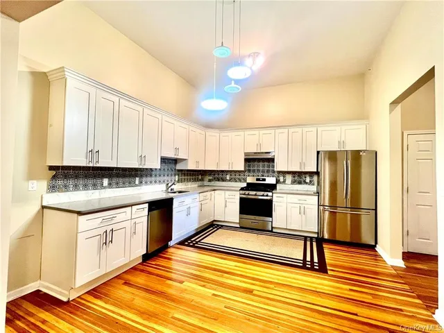a kitchen with granite countertop white cabinets and stainless steel appliances