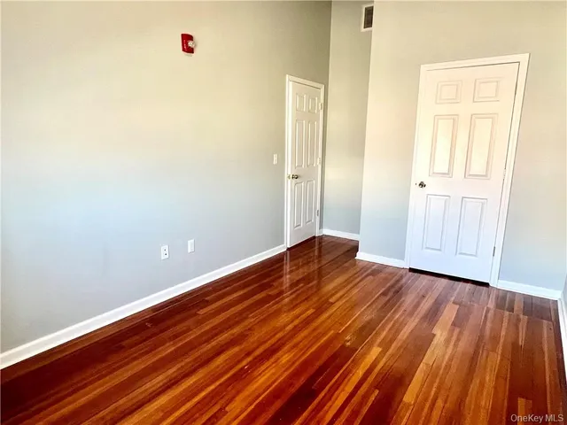 a view of an empty room with wooden floor and closet