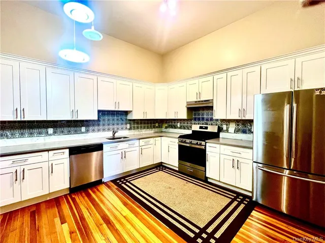 a kitchen with granite countertop a refrigerator stove top oven and sink