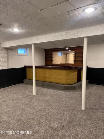 a view of an empty room with kitchen and window