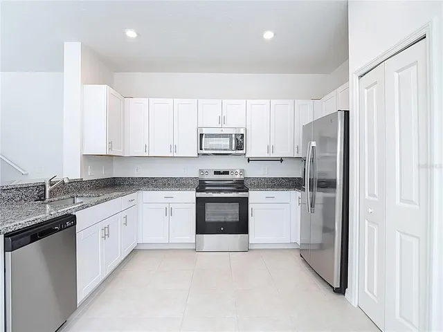 a kitchen with granite countertop white cabinets and stainless steel appliances