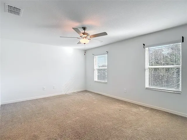 an empty room with a window and a ceiling fan