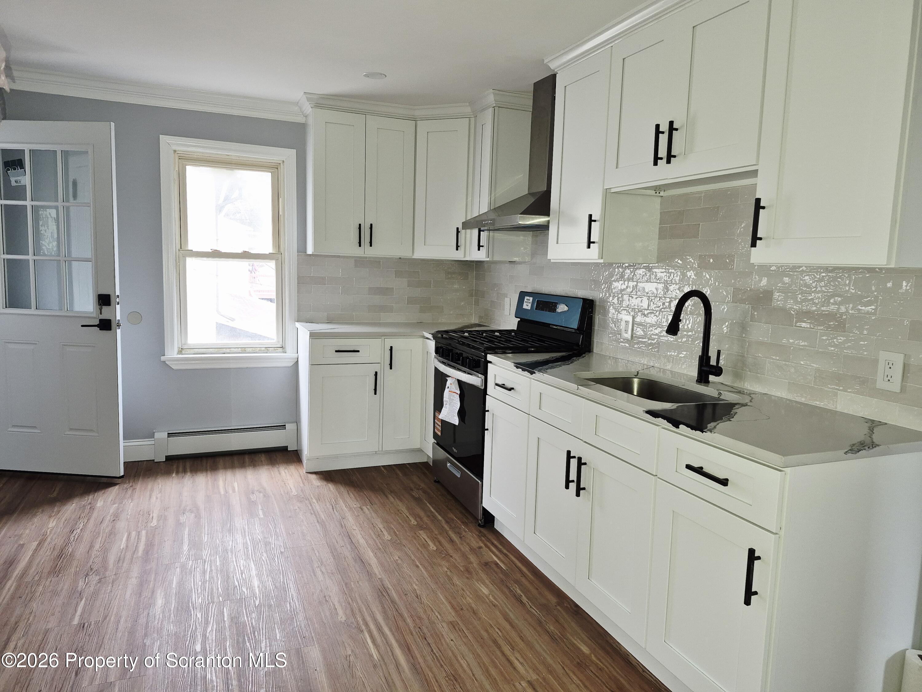 1132 Lloyd Street Scranton, PA 18508 - Photo 21 of 37 a kitchen with granite countertop a sink wooden floor and white cabinets