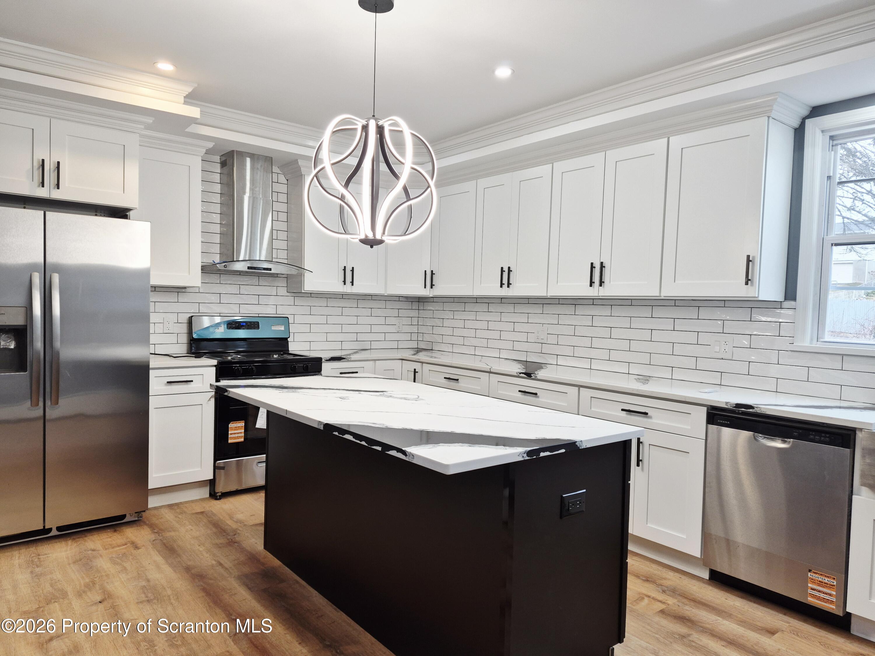 1132 Lloyd Street Scranton, PA 18508 - Photo 6 of 37 a kitchen with stainless steel appliances granite countertop a sink a stove a refrigerator and island with wooden floor