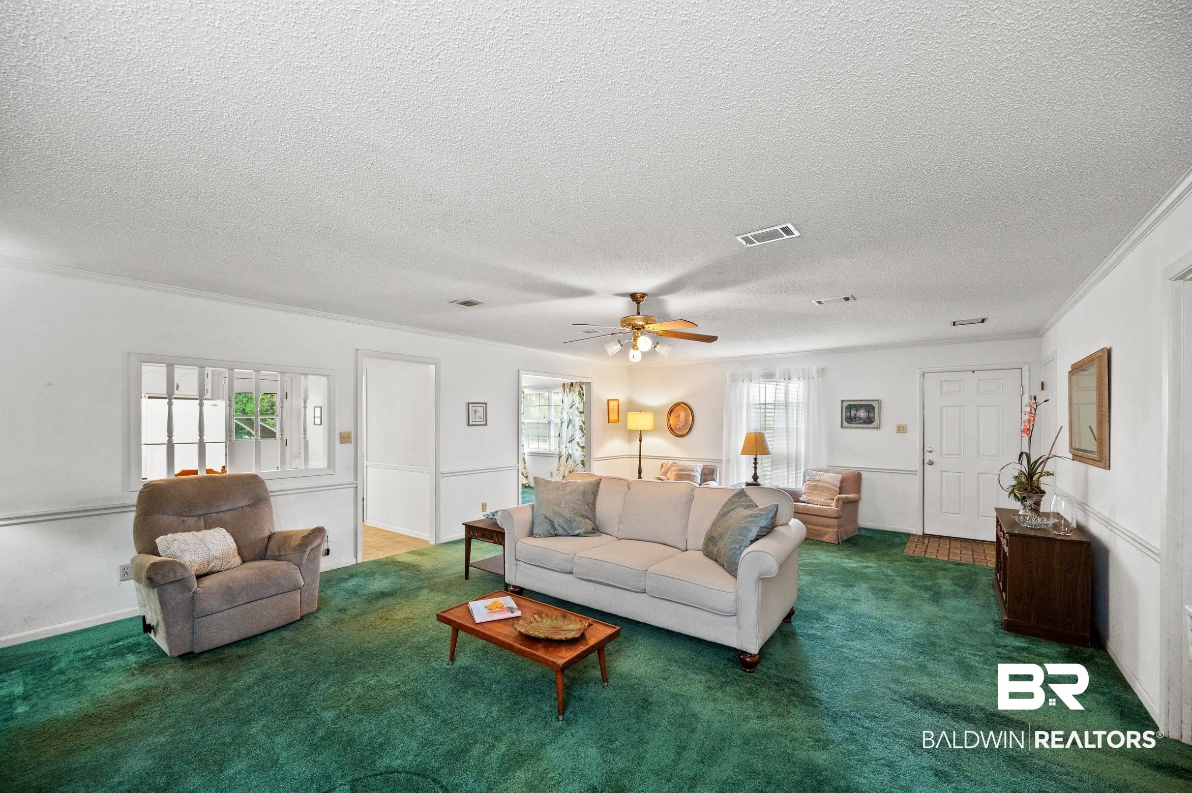 15600 Fackler Road Loxley, AL 36551 - Photo 12 of 51 Carpeted living room with a wealth of natural light, ornamental molding, a textured ceiling, and ceiling fan