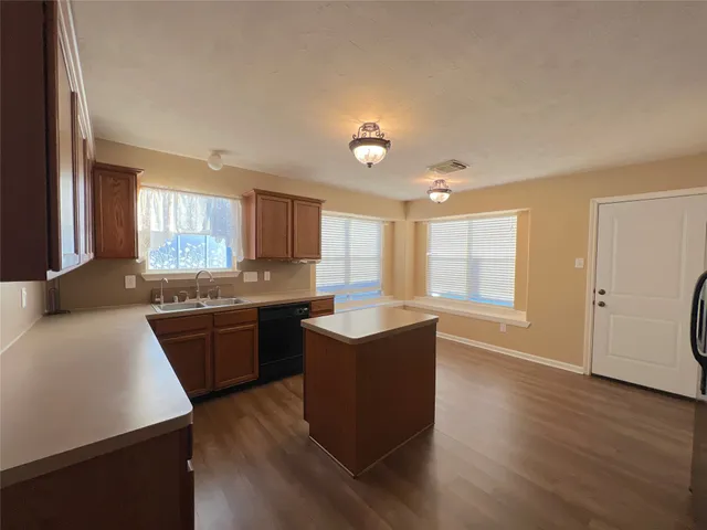 a kitchen with stainless steel appliances granite countertop a sink dishwasher stove and wooden cabinets with wooden floor