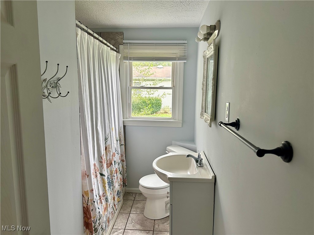 4664 Kennedy Road Lowellville, OH 44436 - Photo 7 of 11 Bathroom with tile patterned flooring, a textured ceiling, walk in shower, vanity, and toilet