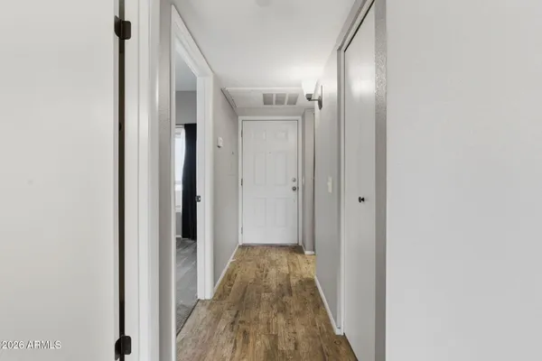 a view of a hallway with wooden floor and a bathroom