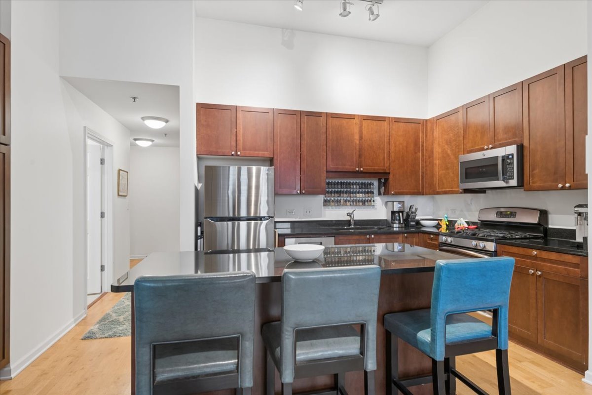 1255 South State Street, Unit 502 Chicago, IL 60605 - Photo 5 of 13 a kitchen with stainless steel appliances granite countertop a stove a refrigerator a sink dishwasher a dining table and chairs