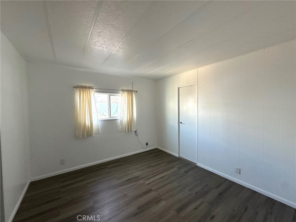15181 Van Buren Boulevard, Unit 57 Riverside, CA 92504 - Photo 15 of 40 an empty room with wooden floor and windows