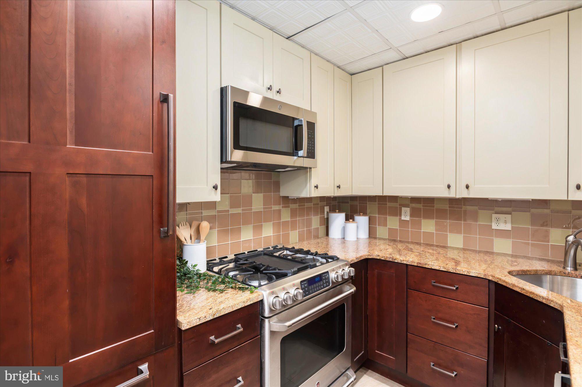 1913 Kalorama Place Northwest, Unit 13 Washington, DC 20009 - Photo 13 of 33 a kitchen with stainless steel appliances granite countertop a stove and a microwave