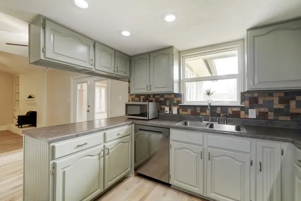 a kitchen with white cabinets sink and window