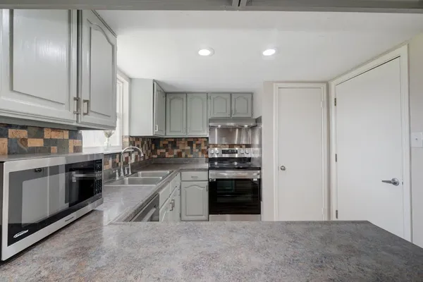 a kitchen with stainless steel appliances granite countertop a stove a sink and a refrigerator