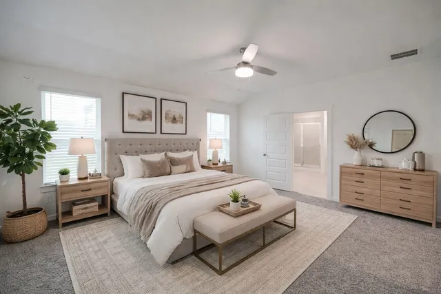 a spacious bedroom with a bed a mirror and potted plant on dresser