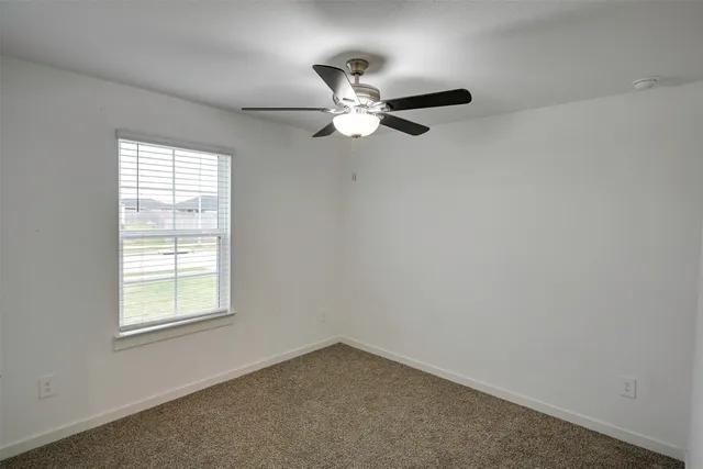 an empty room with a window and a fan