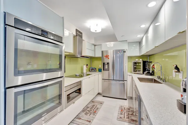 a kitchen with stainless steel appliances granite countertop a refrigerator a stove and a sink