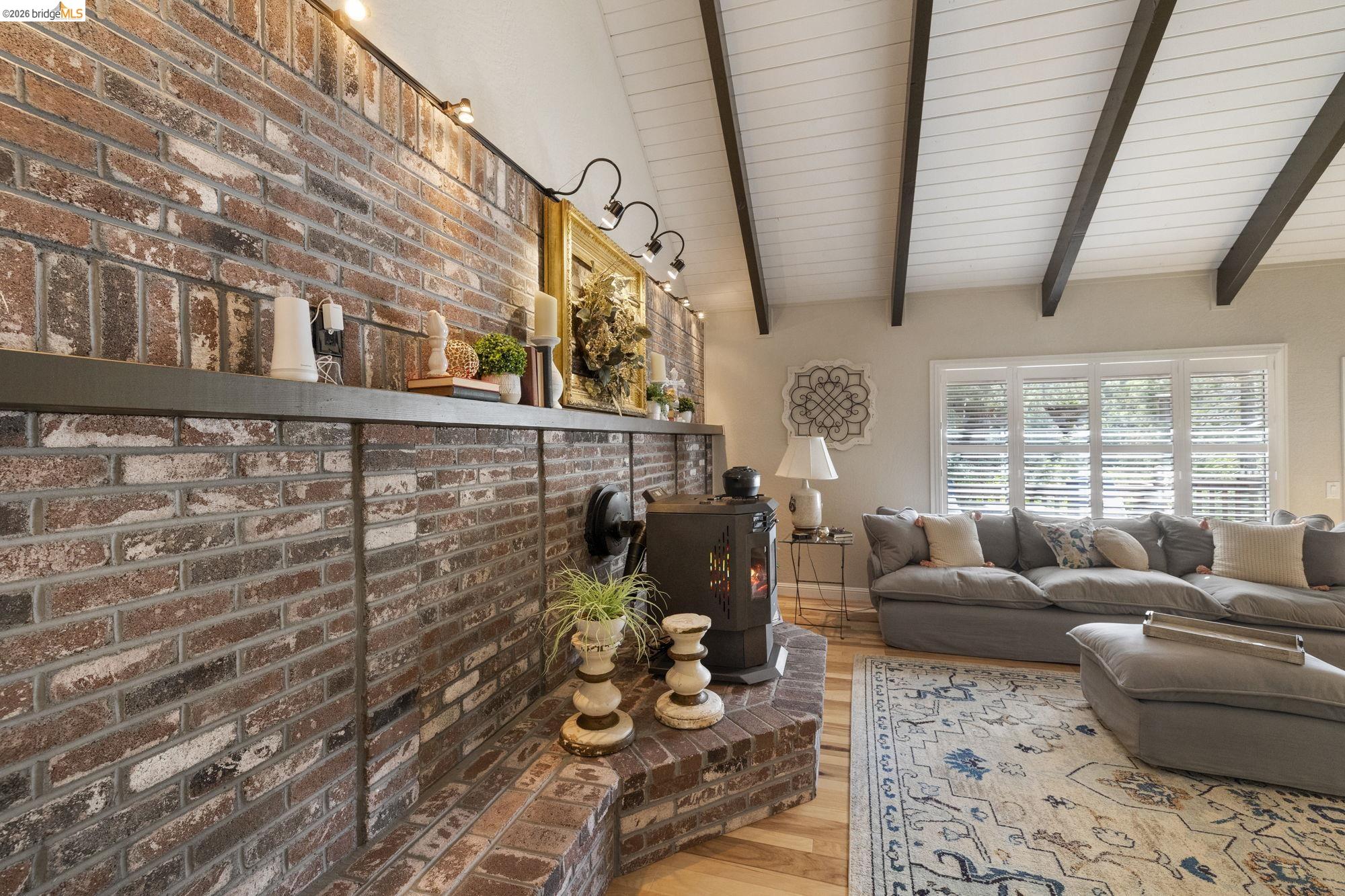 20581 Gerber Road Tuolumne, CA 95379 - Photo 16 of 60 Living area featuring a wood stove, wood finished floors, and brick wall