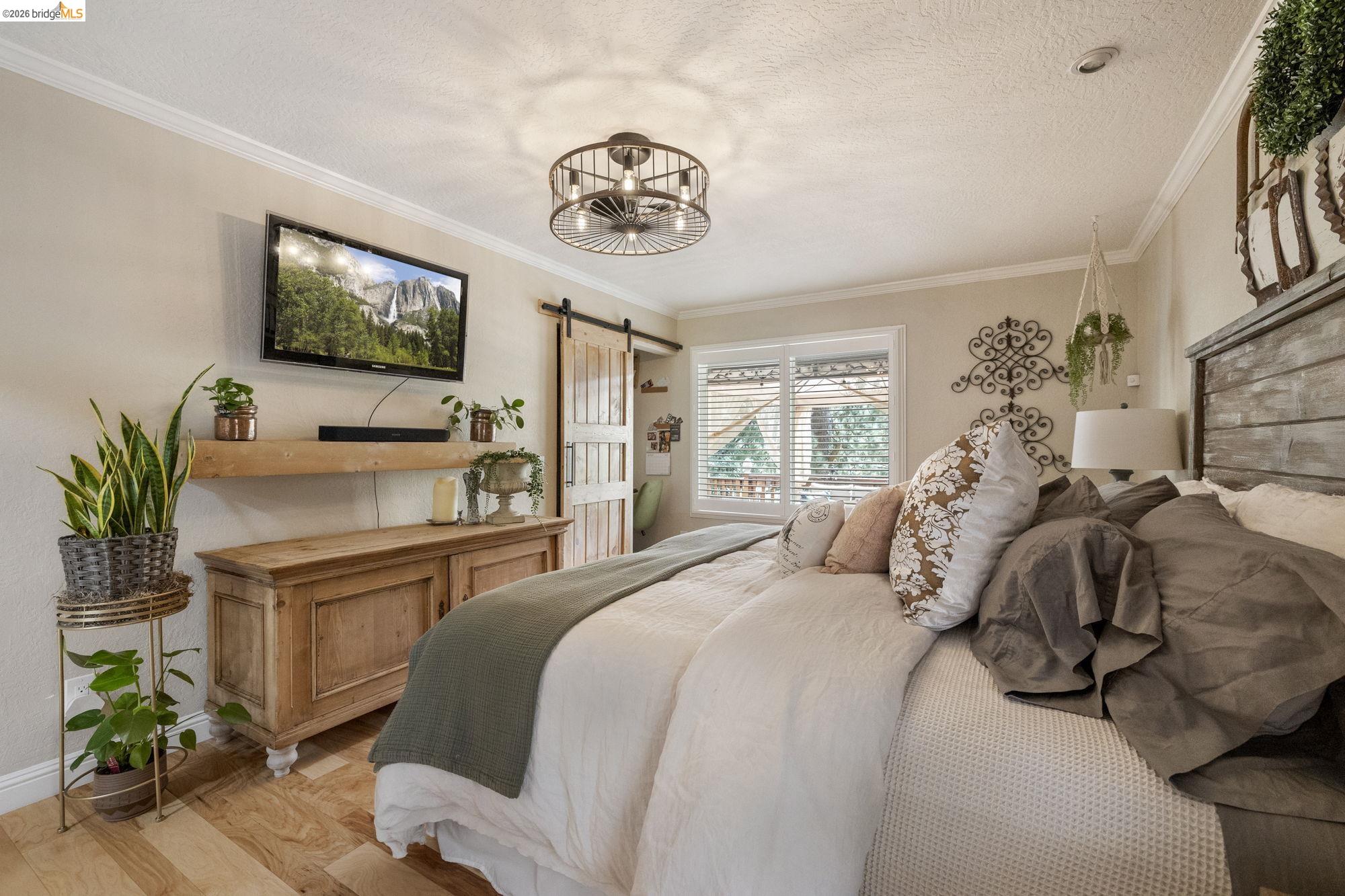 20581 Gerber Road Tuolumne, CA 95379 - Photo 4 of 60 Bedroom with a barn door, crown molding, wood finished floors, and a textured ceiling