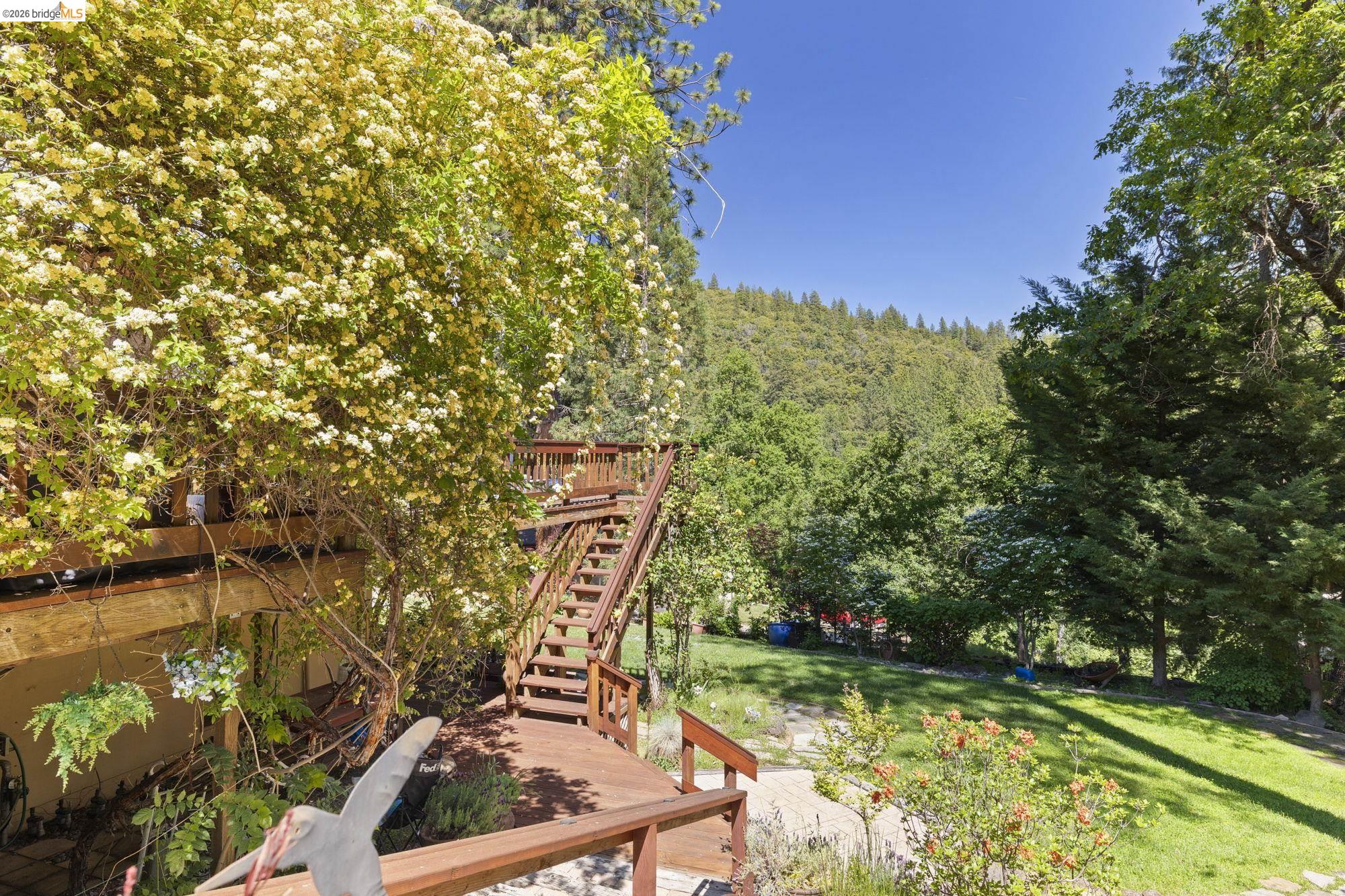 20581 Gerber Road Tuolumne, CA 95379 - Photo 47 of 60 View of green lawn featuring a wooden deck, stairway, and a view of trees