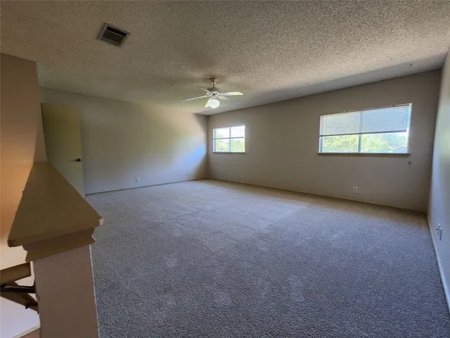 an empty room with windows and fan