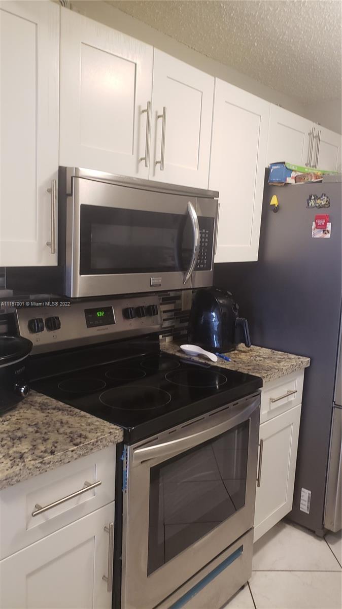 3120 North Pine Island Road, Unit 203 Sunrise, FL 33351 - Photo 2 of 8 a kitchen with a stove and a microwave