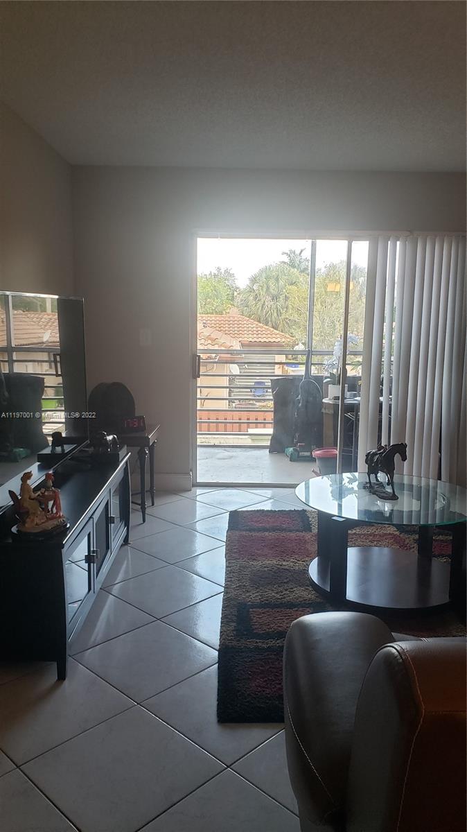 3120 North Pine Island Road, Unit 203 Sunrise, FL 33351 - Photo 4 of 8 a living room with couches a coffee table and a stove with wooden floor